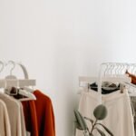 Two rails of neutral-toned clothing against a white wall