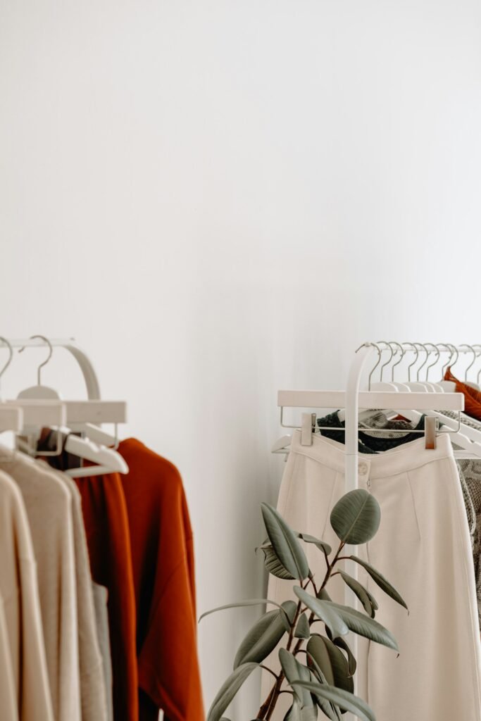Two rails of neutral-toned clothing against a white wall