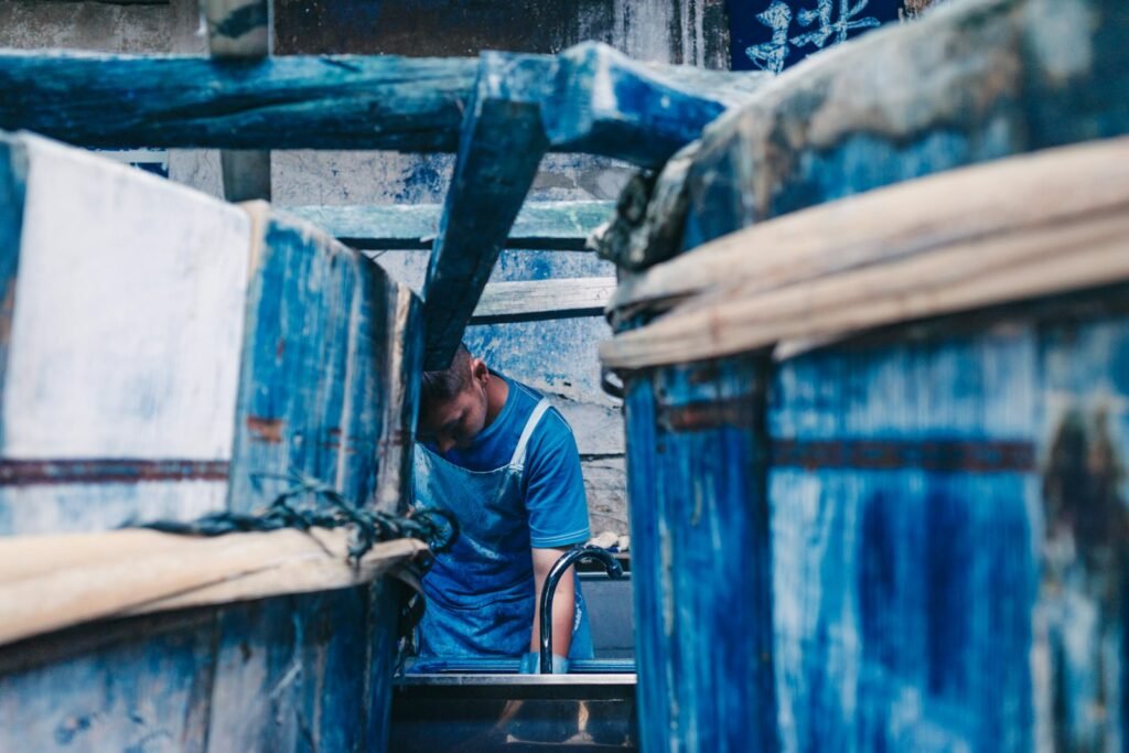 A dyer at work between indigo vats in a dyeing workshop