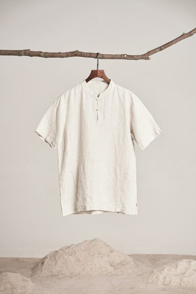 A natural linen shirt hanging from a branch against warm sand