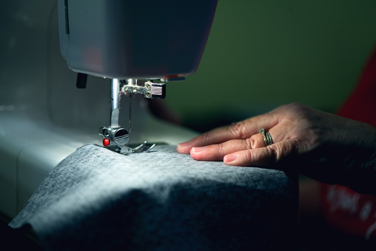 Hands guiding cloth through a sewing machine